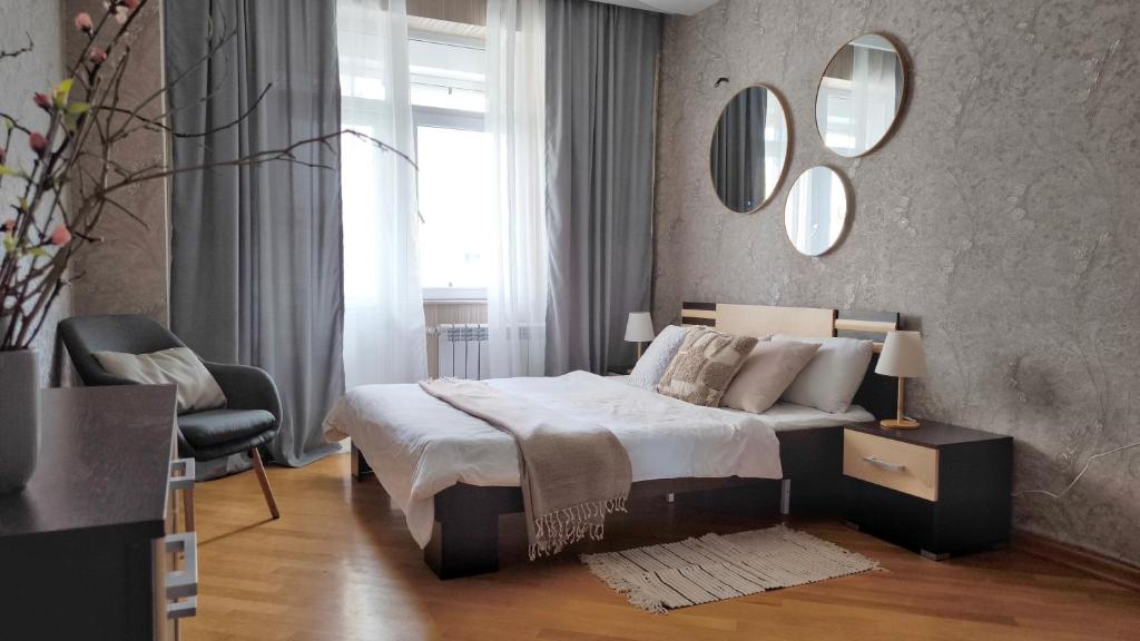 a bedroom with a bed and a chair and mirrors at Апартаменты возле метро in Baku