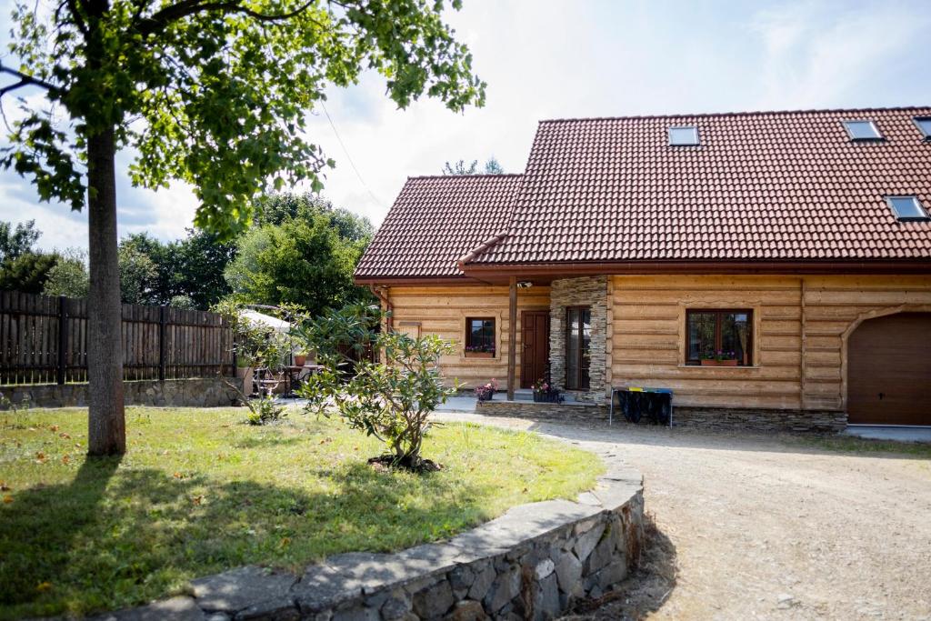 a wooden house with a stone wall in front of it at Doberek Noclegi w Beskidzie Niskim in Kobylanka