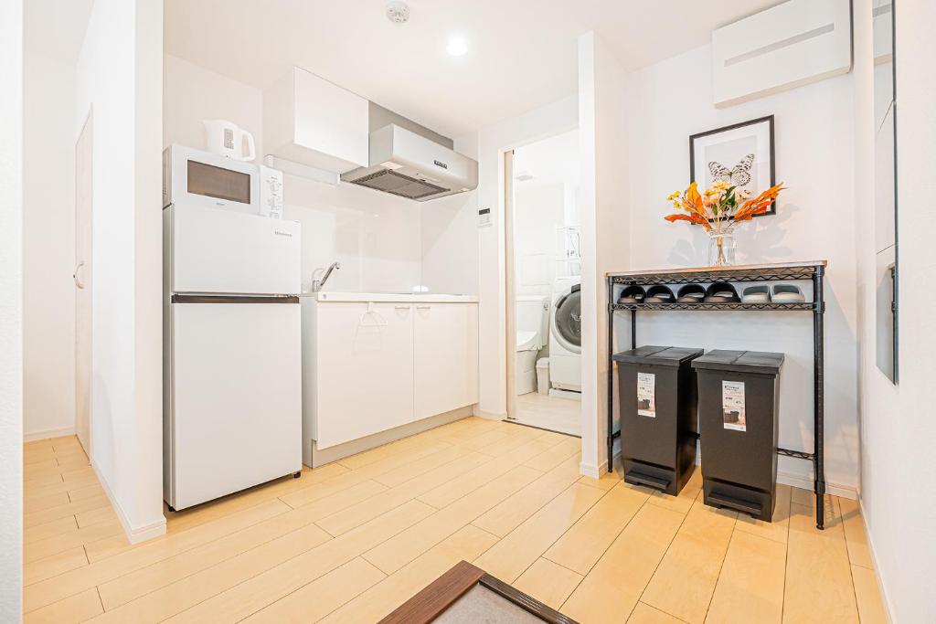 a white kitchen with a refrigerator and a fireplace at New-built APT at Asakusa-Skytree area with Tranquil block in Tokyo