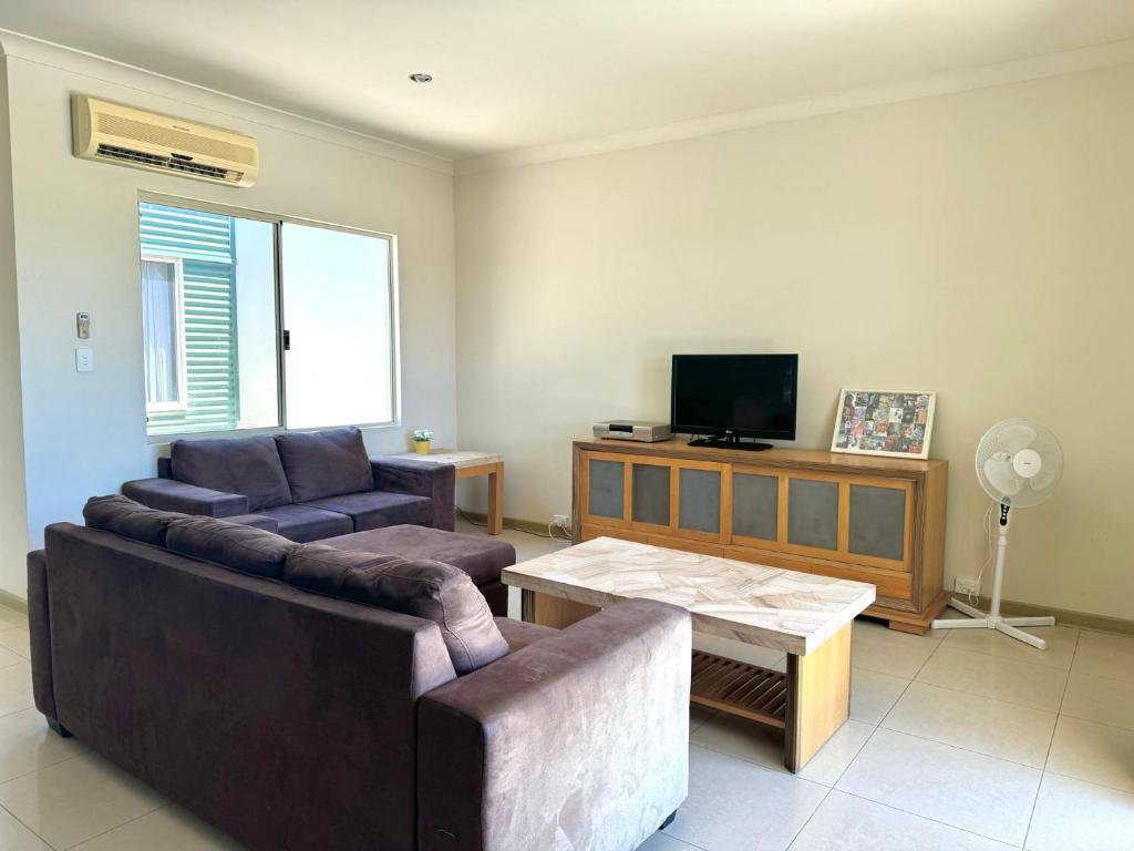 a living room with a couch and a table and a tv at Oh Bouy, Unit 62 Seafront Estate in Jurien Bay