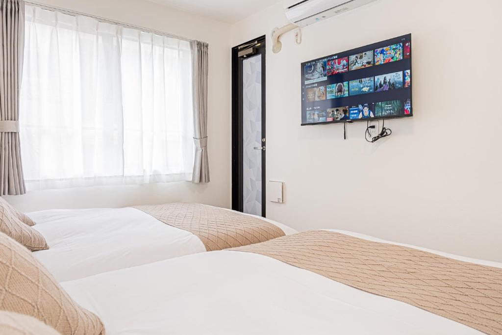 two beds in a bedroom with a tv on the wall at New-built APT at Asakusa-Skytree area with Tranquil block in Tokyo