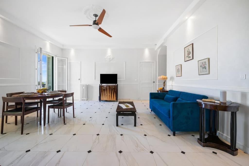 un salon avec un canapé bleu et une table dans l'établissement Alexandra Palace, Appartement Belle Époque Menton, vue mer, parking, à Menton