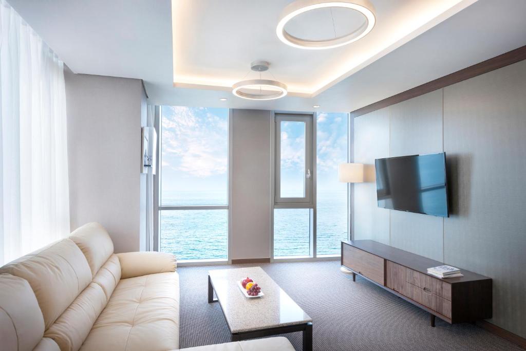 a living room with a white couch and a large window at Hotel Regent Marine The Blue in Jeju