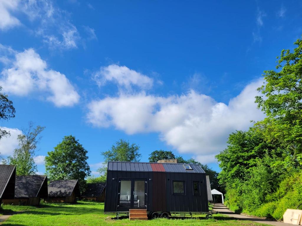 a black tiny house in a field with trees at Bigge Elements Tinyhaus 5 "Wasser" in Olpe