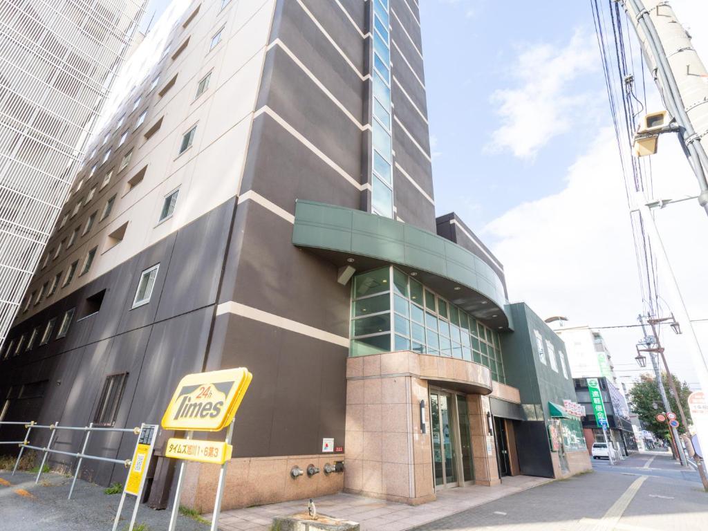 Un edificio alto con un cartel delante. en Tabist ASAHIKAWA STATION HOTEL, en Asahikawa