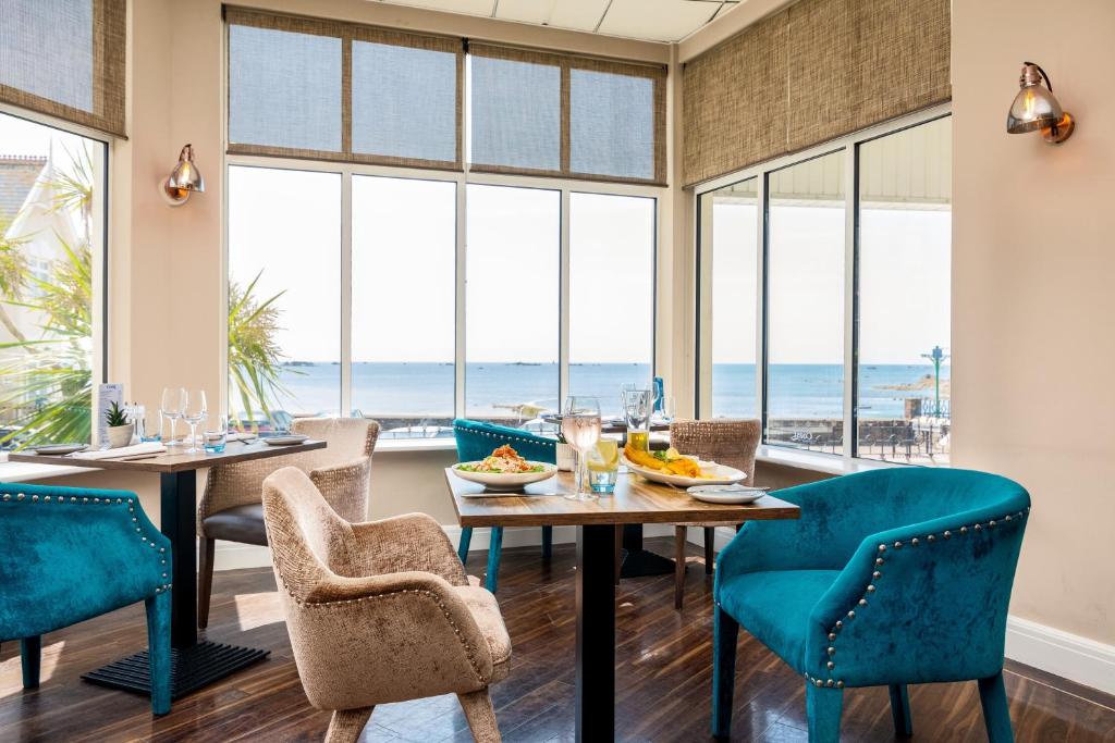 a dining room with a table and chairs with a view of the ocean at Ommaroo Hotel in Saint Helier Jersey