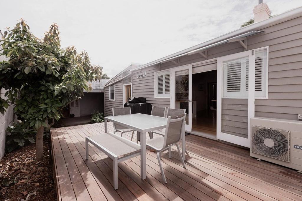 eine Terrasse mit Tisch und Stühlen auf einem Deck in der Unterkunft Workers cottage on Wellington in Hobart