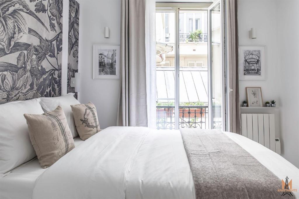 une chambre blanche avec un grand lit et une fenêtre dans l'établissement Montmartre Apartments Chagall, à Paris