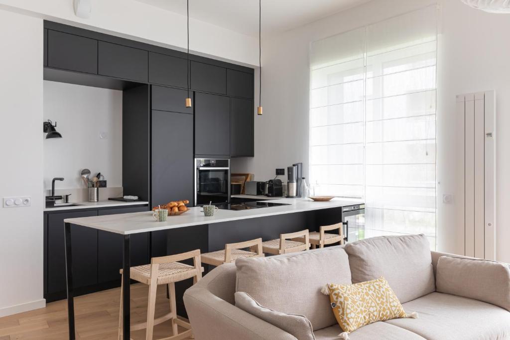 un salon avec un canapé et une cuisine dans l'établissement Le Bacchus - Charmant appt avec vue sur la Vilaine, à Rennes