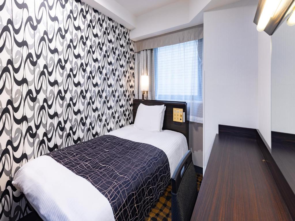 a hotel room with a bed and a patterned wall at APA Hotel Ningyocho Ekikita in Tokyo