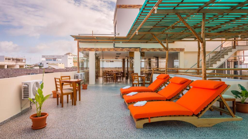 einen Balkon mit orangefarbenen Stühlen und Tischen auf einem Gebäude in der Unterkunft Hotel Flamingo in Puerto Ayora