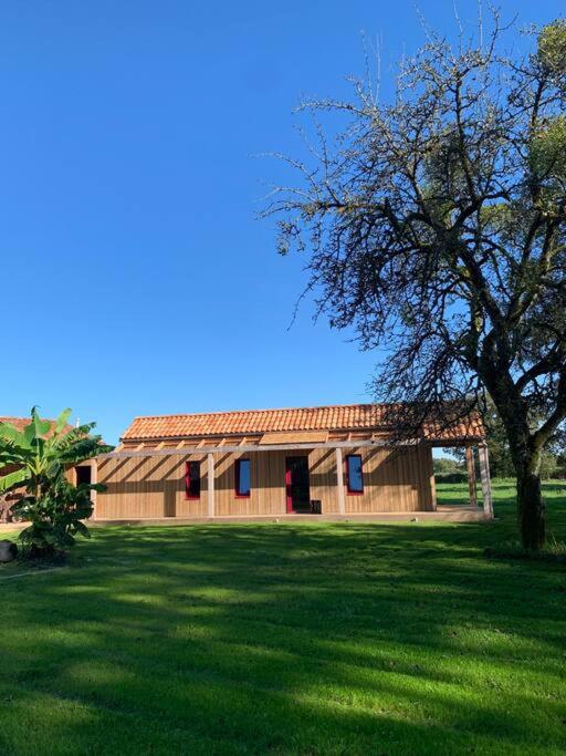 une maison en bois avec un arbre dans un champ dans l'établissement la maison des Poteries, à Chanteloup-les-Bois