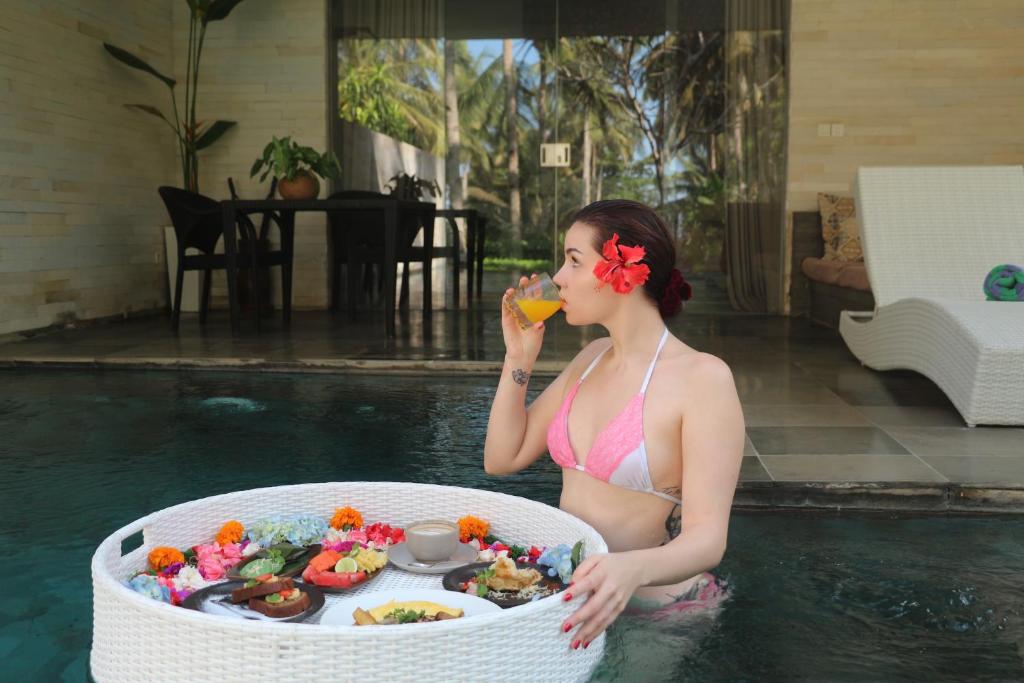 a woman in a swimming pool eating food at Kelapa Retreat & Spa in Pulukan