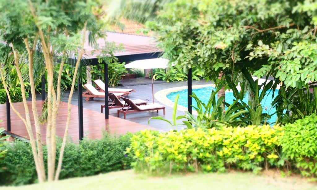 a resort with a swimming pool with benches and trees at Tropicana Lanta Resort in Ko Lanta