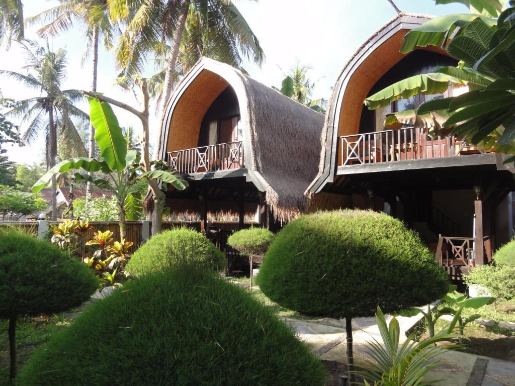 a house with a thatched roof and a garden at Villas Ganjor in Gili Meno
