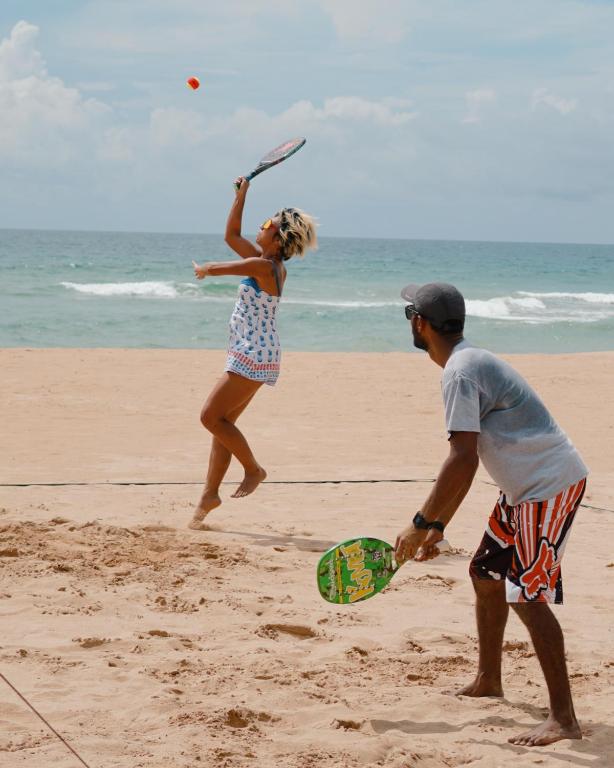 a man and a woman playing frisbee on the beach at Nyne Hotels Rock Villa, Bentota in Bentota
