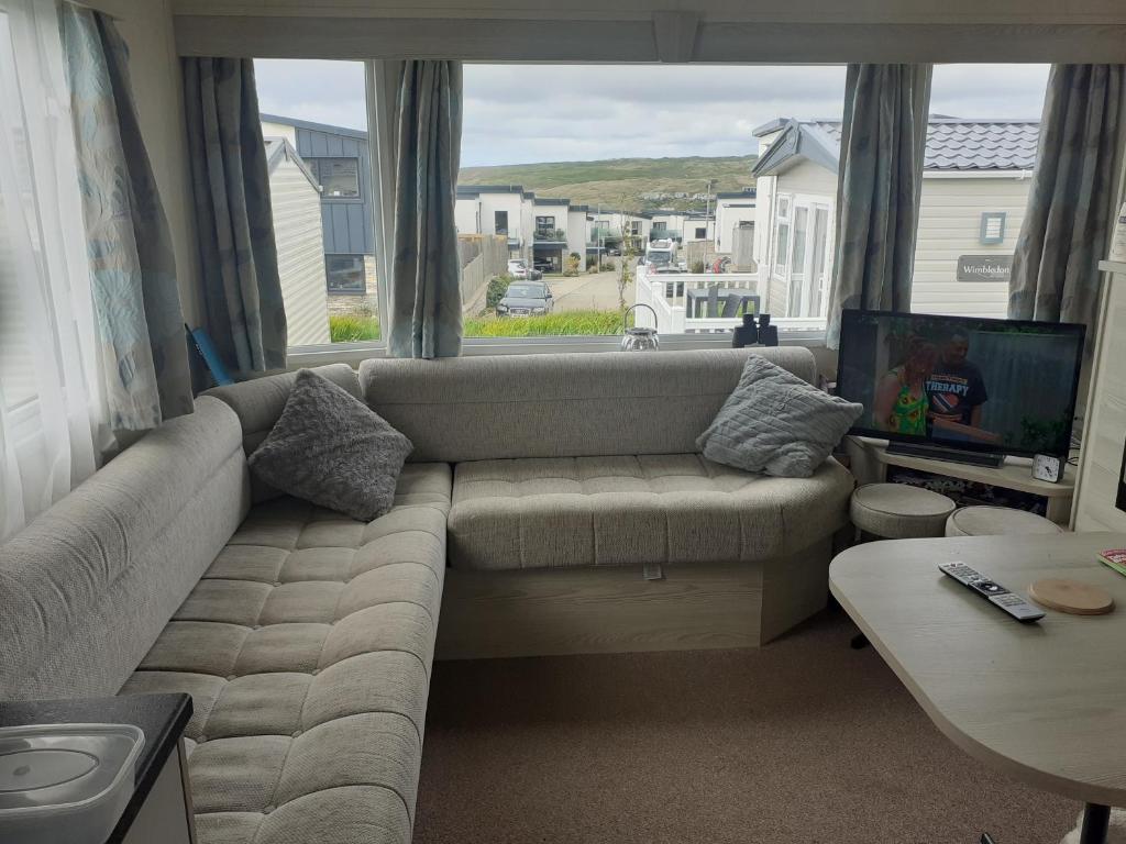 a living room with a couch and a large window at PerranporthCaravan 2bedroom Tv GasFire in Perranporth