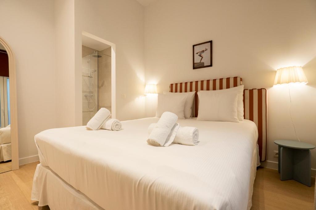 Un dormitorio con una gran cama blanca con toallas. en SHWAY - The Captain's View, en Amberes
