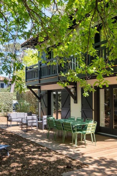 un groupe de chaises vertes et une table devant un bâtiment dans l'établissement Villa Bellevue - Pyla sur Mer - Proche de la plage, à La Teste-de-Buch