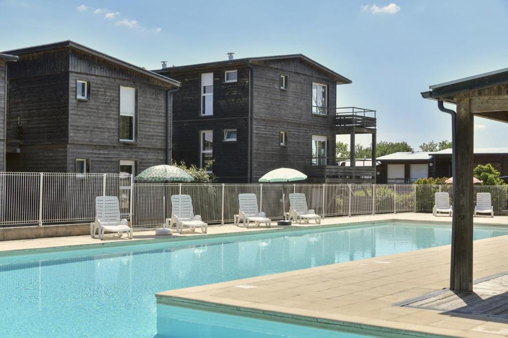 a swimming pool with lounge chairs and a building at Vacancéole - Domaine de Saint Orens in Montréal
