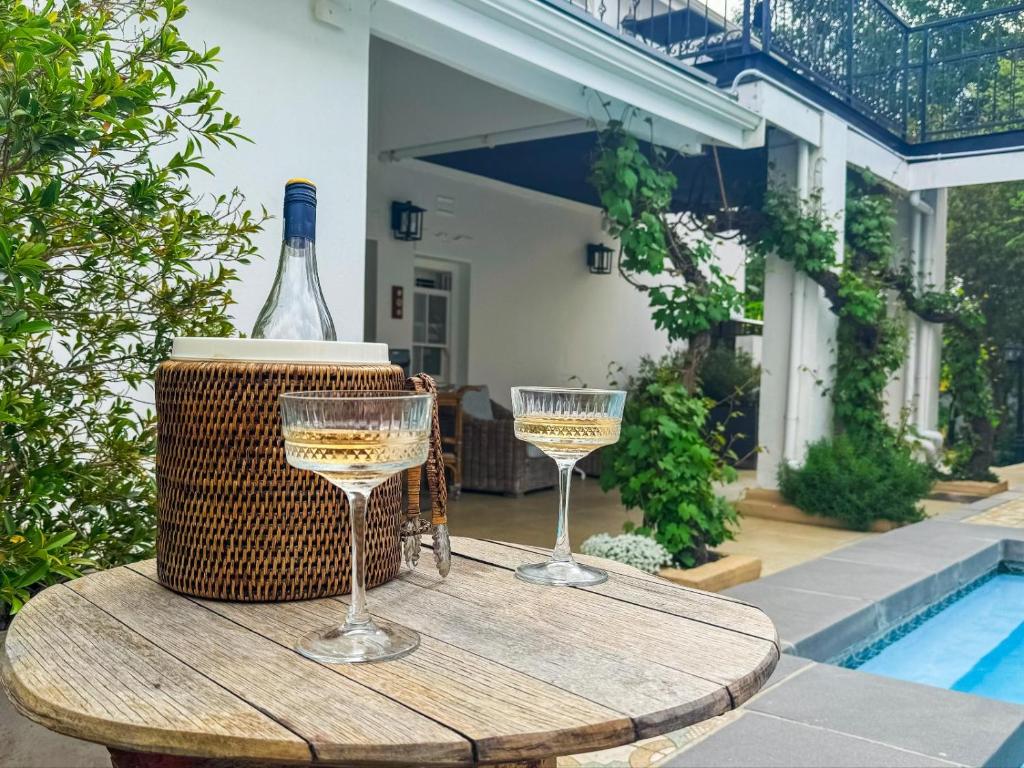 a table with two glasses and a bottle of wine at Le Petit Paris in Franschhoek