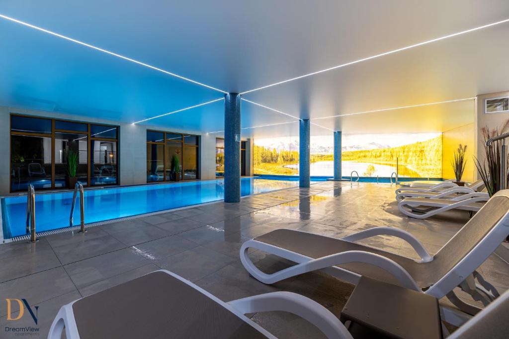 a swimming pool with two lounge chairs in a house at Apartament Dream View SPA in Szklarska Poręba