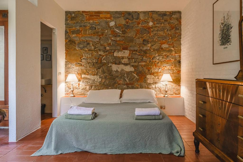 une chambre avec un lit et un mur en pierre dans l'établissement Podere Mencoini, stylish villa with private pool and olive garden, à Scrofiano