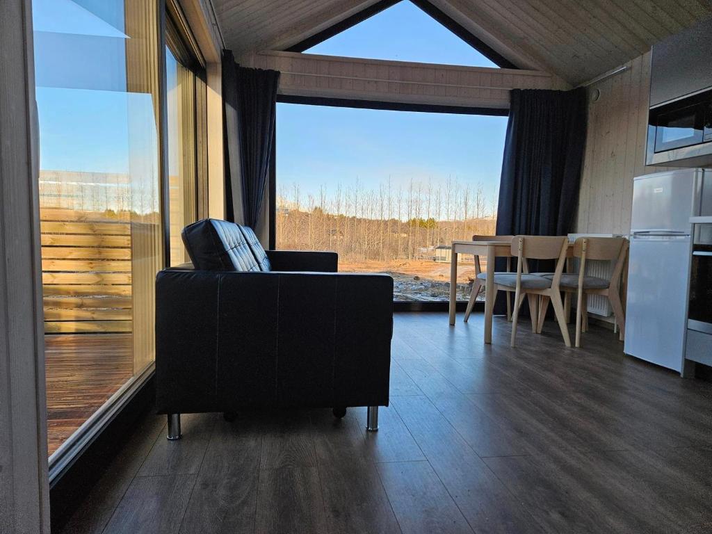 ein Wohnzimmer mit einer Couch und einem Tisch und einem großen Fenster in der Unterkunft Úthlíd Cottages in Úthlid