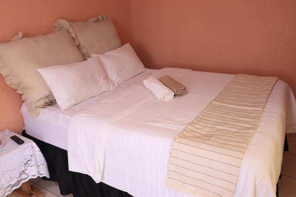a bed with white sheets and pillows on it at Thenjwas Sleep-Over Lodge in Nelspruit