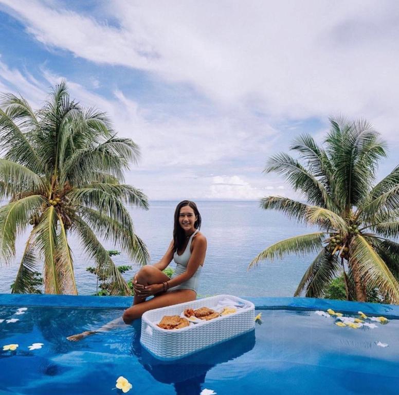 a woman sitting on the edge of a pool with a tray of food at Bintana Sa Paraiso in Mambajao