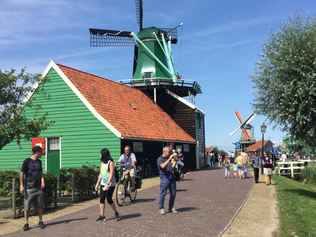 a group of people standing in front of a windmill at Stay overnight at Windmill Village Zaanse Schans - Amsterdam in Zaandam