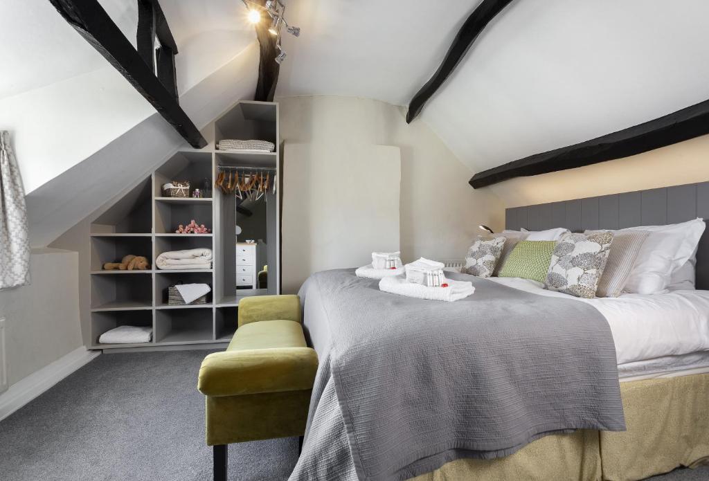 a bedroom with a large bed and a yellow chair at Spring Cottage in Painswick