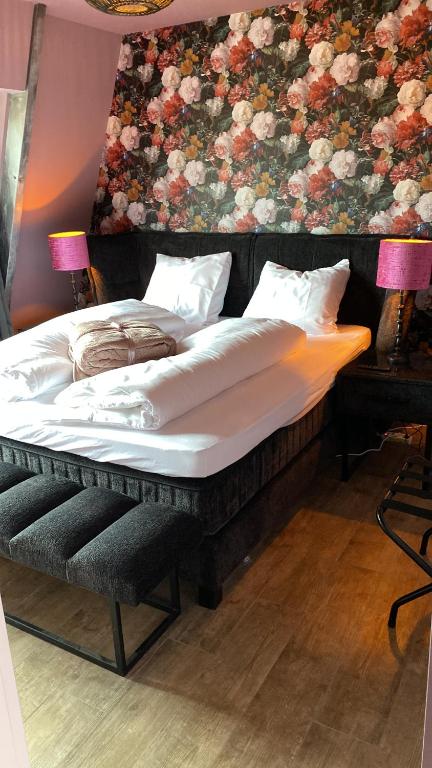 a large bed in a room with a floral wall at Boutique Hotel Noordeinde in Rijnsburg