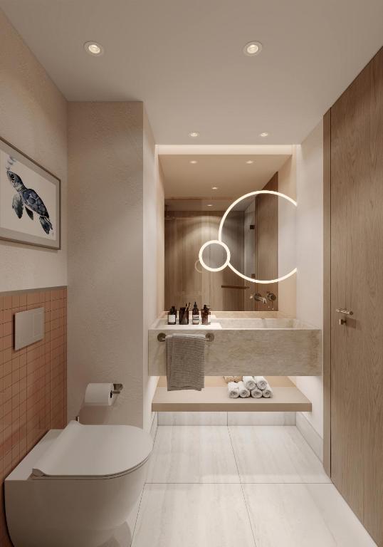 a bathroom with a toilet and a round mirror at Ducale Lara - Ultra All Inclusive in Lara