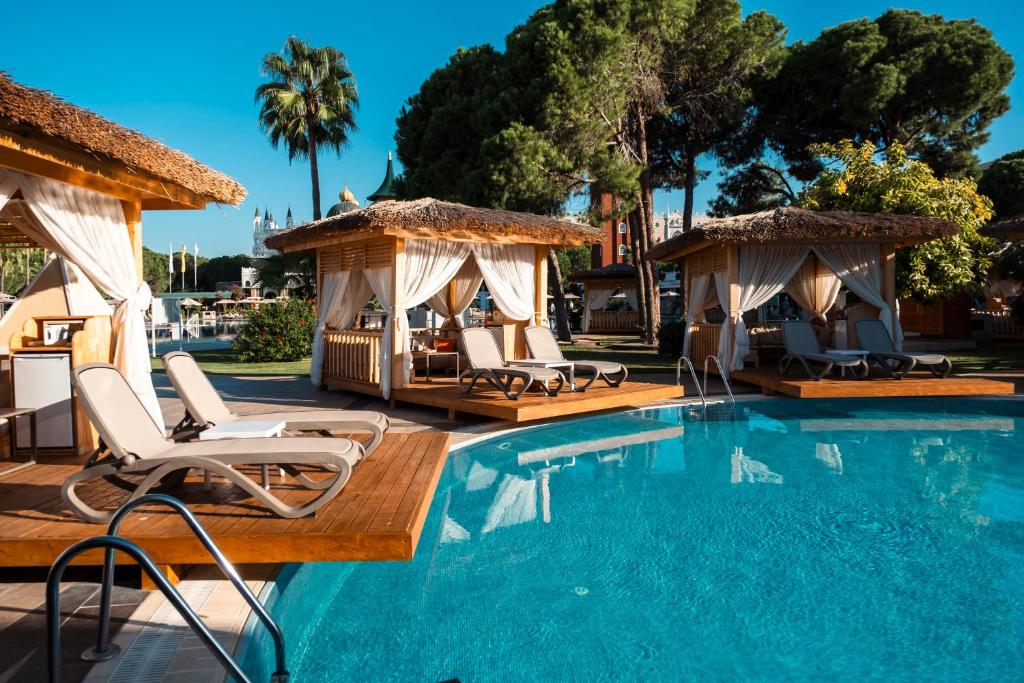a swimming pool with chairs and gazebos at Ducale Lara - Ultra All Inclusive in Lara