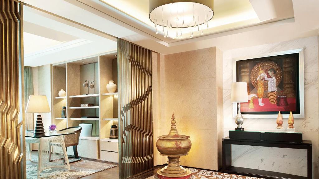 A refined hotel sitting area with a writing desk, display shelving, and decorative fireplace-style console.