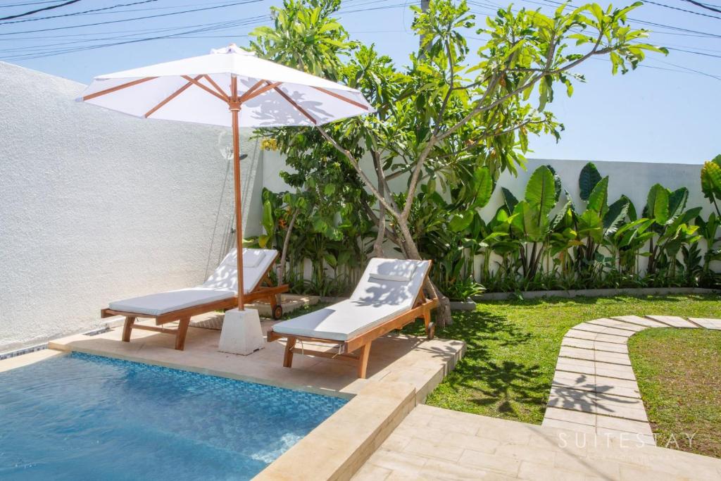a pair of chairs and an umbrella next to a pool at Two Bedroom Villa with Outdoor Pool in Umalas