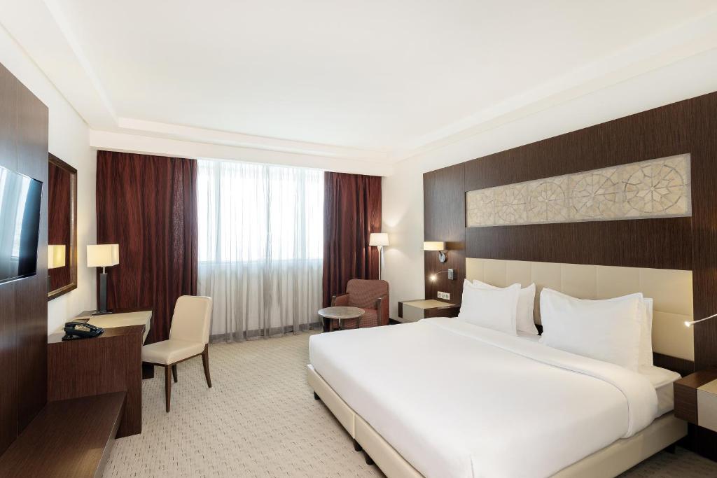 una camera d'albergo con un grande letto e una TV di Radisson Blu Hotel & Convention Center, Tunis a Tunisi