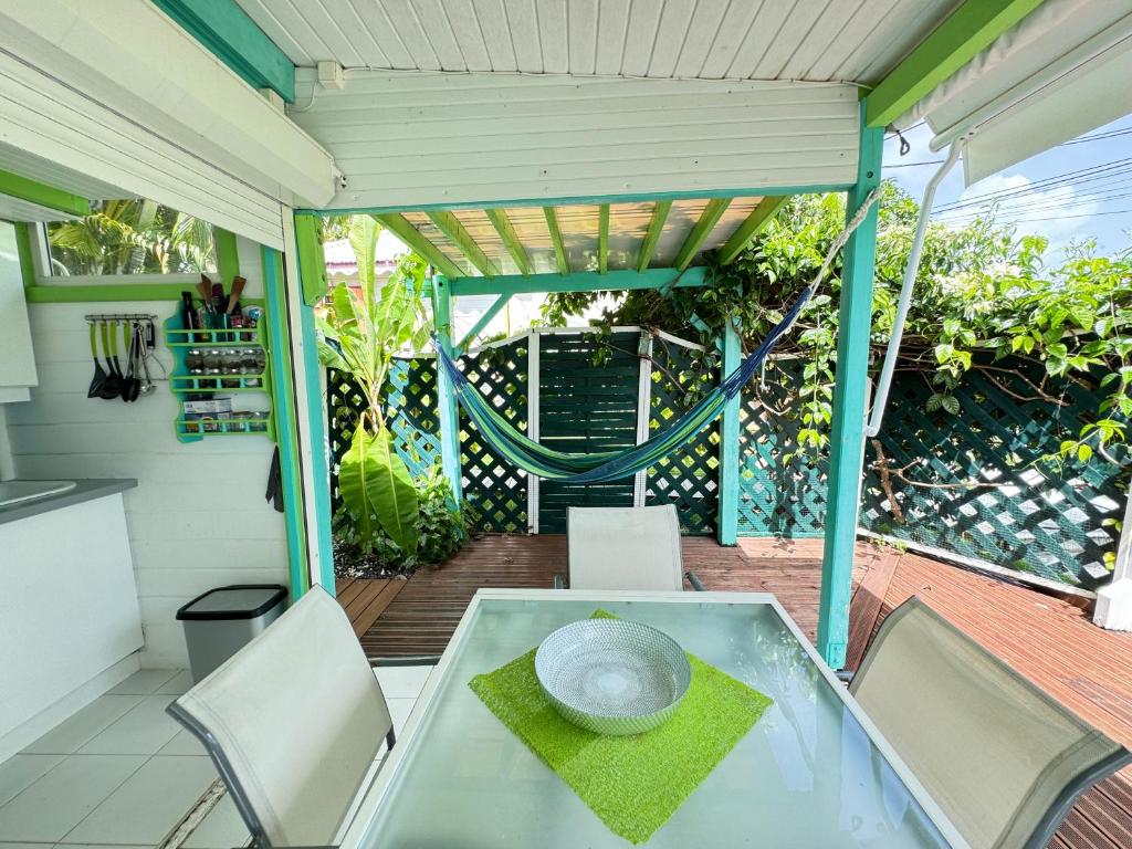 a patio with a glass table and chairs on a balcony at Alpinia bungalow in Sainte-Anne