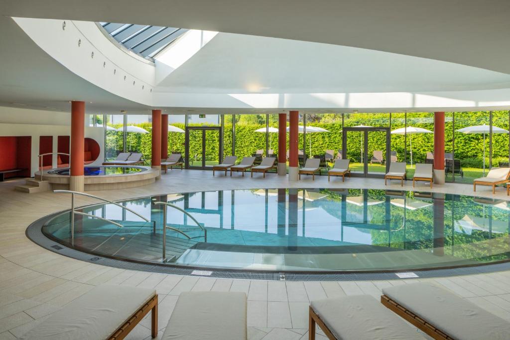 una grande piscina in un edificio con sedie e tavoli di Villa Seilern Vital Resort a Bad Ischl