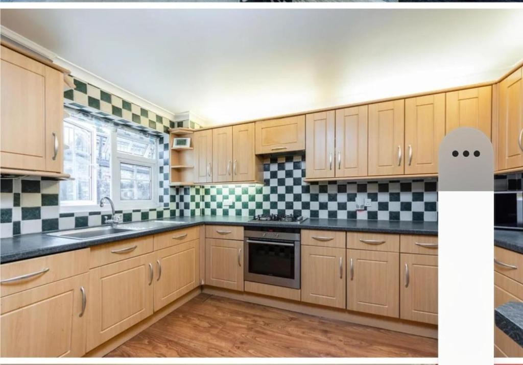 a kitchen with wooden cabinets and black and white tiles at Purley House-Sleeps 8-Near Gatwick-Games Room in Purley