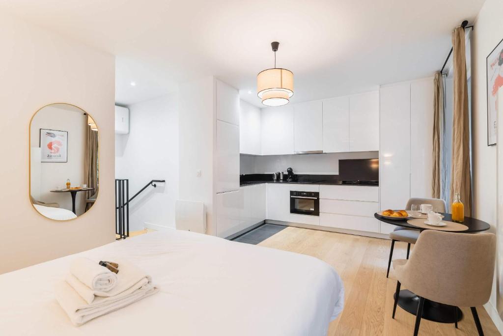 une chambre blanche avec un grand lit et une table dans l'établissement Studio refait a neuf montmartre - paris 18 - 2P - FLAT-GUEST, à Paris