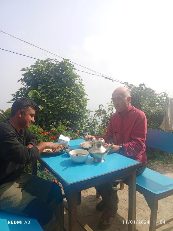 two men sitting at a table eating food at Unique point home stay in Nagarkot