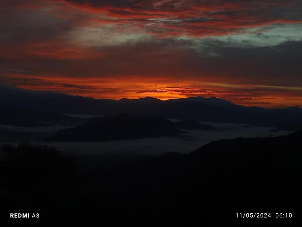 a sunset over the mountains with a layer of clouds at Unique point home stay in Nagarkot