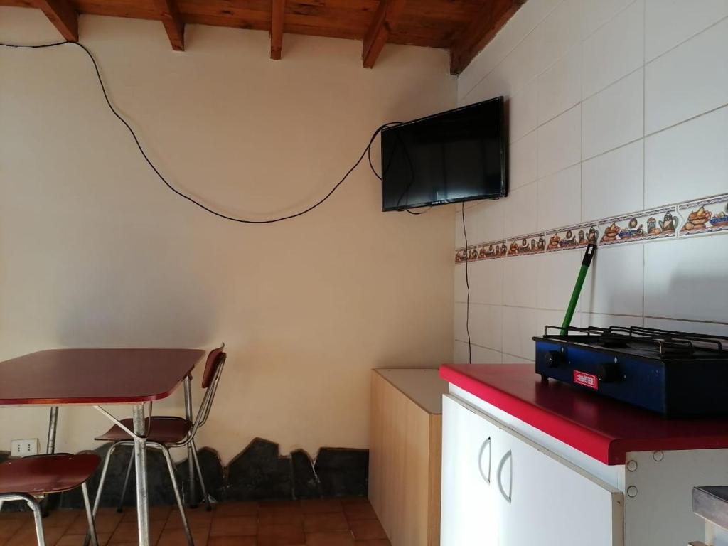 a kitchen with a table and a tv on the wall at Departamentos Altamira in Cobquecura