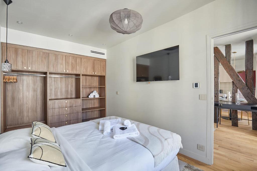 une chambre blanche avec un lit et une télévision dans l'établissement Cosi apartment Bastille - Le Marais, à Paris