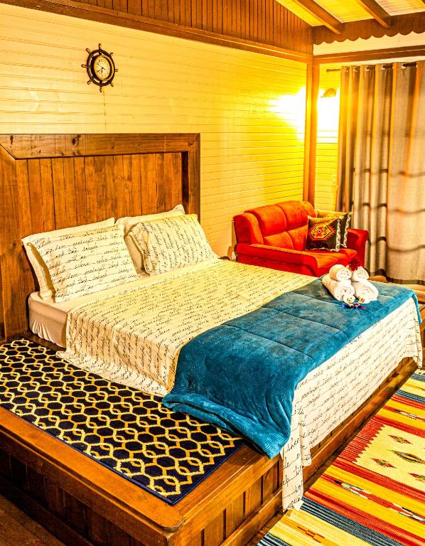 a bedroom with a large bed and a red chair at Pousada Casa do Oscar in Governador Celso Ramos