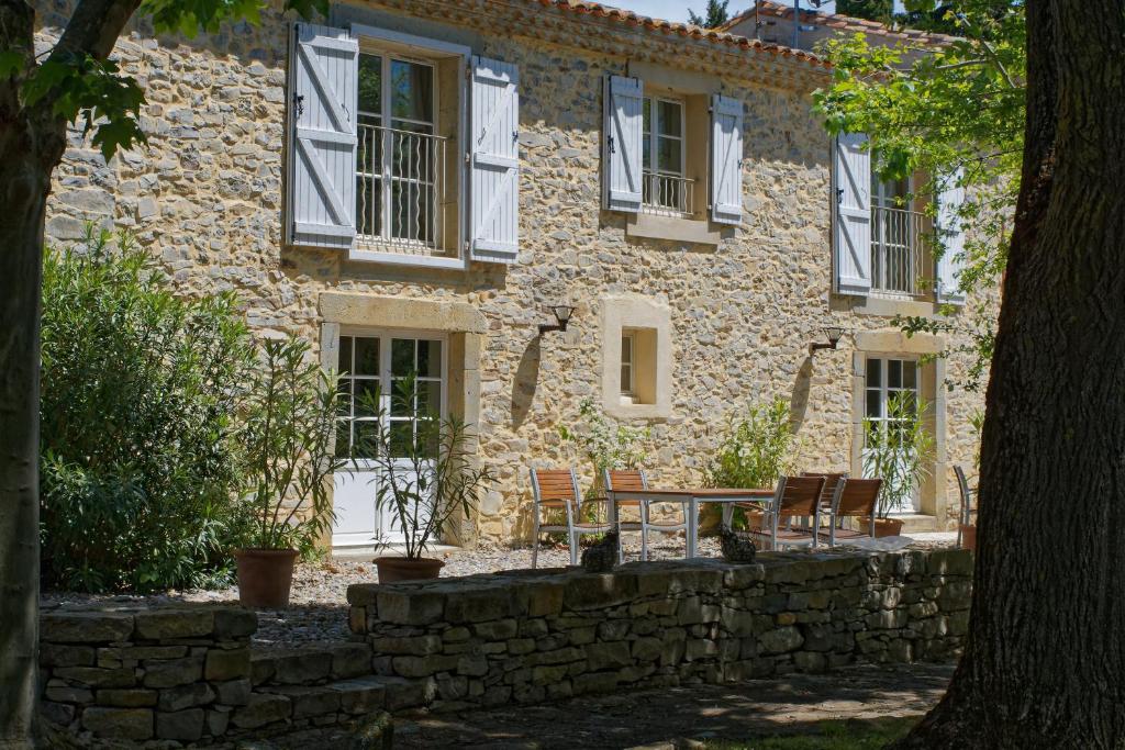 - un bâtiment en pierre avec des chaises et une table devant dans l'établissement Domaine de Curé, à Conques-sur-Orbiel