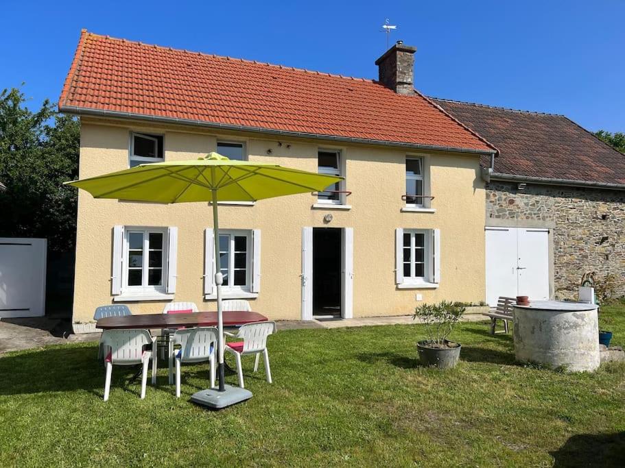 une table avec un parasol vert devant une maison dans l'établissement Ma Rober Rit, à Saint-Germain-sur-Ay