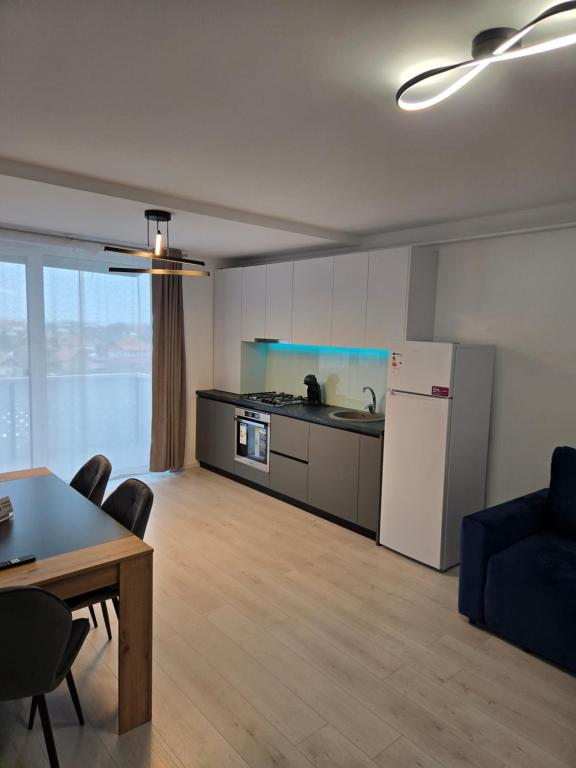 a kitchen and a living room with a table and a refrigerator at Apartament zona aeroport in Sînnicoară